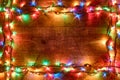 Frame of Christmas lights or colorful garland on wooden background. Bright and colorful New Year festive decorations Royalty Free Stock Photo
