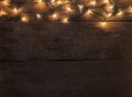 Frame of Christmas lights on old wooden desk background and empty space for text. Top view with copy space