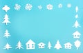 Frame made of white paper figures - houses, Christmas trees, snowflakes on a blue background Royalty Free Stock Photo