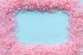 Frame of coarse crystals of pink sea salt on a blue background with copy space Royalty Free Stock Photo