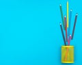 Frame by colored pencils scattered from holder on blue background. Top view. Space for text. School and education background Royalty Free Stock Photo