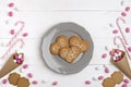 Frame colorful candies, striped lollipops and cookies in the form of heart on plate. Top view, white wooden background.