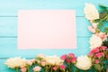 Frame of colorful roses on blue wooden background with paper card and copy space. Top view and selective focus. Mock up Royalty Free Stock Photo