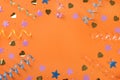 Frame of colorful serpentine streamers and confetti on orange background, flat lay. Space for text