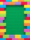 Frame of colorful toy bricks on green construction plate