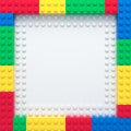 Frame of colorful toy bricks on white construction plate
