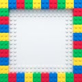 Frame of colorful toy bricks on white construction plate