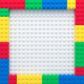 Frame of colorful toy bricks on white construction plate