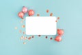 Frame of coral christmas balls and confetti with blank card mockup on blue background