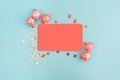 Frame of coral christmas balls and confetti with blank card mockup on blue background