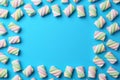 Frame of delicious colorful marshmallows on light blue background, flat lay. Space for text Royalty Free Stock Photo