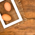 Frame with egg inside on brown wooden background texture