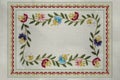 Frame with embroidered satin stitch patterns of branchlets with leaves, and red, blue, purple,cornflowers on the cotton fabric