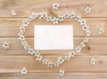 Frame of flowers cherry tree in the shape heart and blank sheet on wooden background with space for text. Top view, flat lay Royalty Free Stock Photo