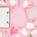 Frame with flowers, clipboard, clips, notebook and scissors on pink background. Flat lay, top view Royalty Free Stock Photo
