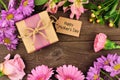 Frame of flowers with Mothers Day gift and tag against rustic wood Royalty Free Stock Photo