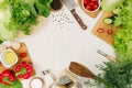 Frame of fresh green salad, red paprika, cherry tomato, pepper, oil and kitchenware on soft white wooden board. Royalty Free Stock Photo