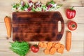 Frame of fresh vegetables around cutting board on wooden background. Healthy natural food on table with copy space on Royalty Free Stock Photo