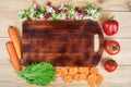 Frame of fresh vegetables around cutting board on wooden background. Healthy natural food on table with copy space on Royalty Free Stock Photo