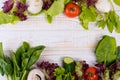 A frame of fresh vegetables, lettuce, tomato, cucumber, mushrooms, parsley, spinach on a white wooden background. Royalty Free Stock Photo