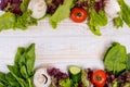 A frame of fresh vegetables, lettuce, tomato, cucumber, mushrooms, parsley, spinach on a white wooden background. Royalty Free Stock Photo