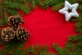 A frame of green fir branches, a white star and three cones on a red background. The concept of Christmas and New year. Space for Royalty Free Stock Photo