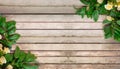 Frame of green leaves and flowers on wooden background. Top view.