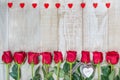 Frame of hearts and red Dutch varietal roses freedom on a light wooden surface. Floral outline with wooden hearts. Idea for