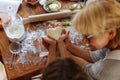 Frame image of a female and kid hands holding dough in heart shape top view. Baking ingredients on the dark table Royalty Free Stock Photo