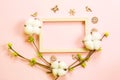 Frame made of cotton flowers, delicate little leaves from open buds on branches-sprouts on a pink background and carved wood