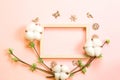 Frame made of cotton flowers, delicate little leaves from open buds on branches-sprouts on a pink background and carved wood