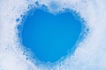 Frame made of detergent foam bubble. Blue background. Heart shape Royalty Free Stock Photo