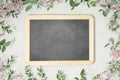 Frame made of eucalyptus branches, spring flowers and empty chalk board on concrete background Royalty Free Stock Photo