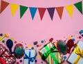 The frame is made of gift boxes, garlands of flags, confetti, cone-shaped caps, blowouts and balloons on a pink background. Royalty Free Stock Photo