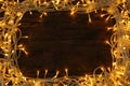 Frame made of glowing Christmas lights on wooden background, top view Royalty Free Stock Photo