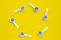 Frame made of medical blue pills with white plastic spoon on yellow background