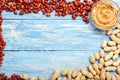 Frame made of nuts peanuts in shell, peeled peanuts, peanut butter in glass plate with copy space in the center on blue wooden Royalty Free Stock Photo