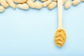 Frame made of nuts peanuts in shell and wooden spoon with creamy peanut butter with copy space on blue colored background. Flat Royalty Free Stock Photo