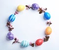 Frame made of painted Easter eggs and blossoming branches on white background, top view. Royalty Free Stock Photo