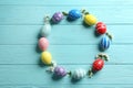 Frame made of painted Easter eggs and flowers on wooden background, flat lay. Royalty Free Stock Photo