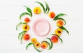 Frame made of peaches and peach tree leaves with pink empty plate in center. Flat lay with copy space. Whole peaches and half Royalty Free Stock Photo