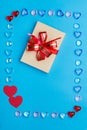 In a frame made of pebbles of hearts on a blue background  a box with a bow. Copy the place Royalty Free Stock Photo