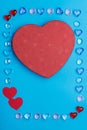 In a frame made of pebbles of hearts on a blue background, a box in the shape of a heart. Royalty Free Stock Photo