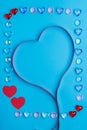 In a frame made of pebbles of hearts on a blue background, a ribbon in the shape of a heart. Royalty Free Stock Photo