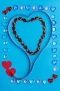 In a frame made of pebbles of hearts on a blue background, a ribbon in the shape of a heart. Royalty Free Stock Photo