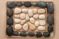 Frame made of rope lying on the sand among the black and white stones Royalty Free Stock Photo