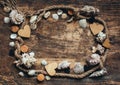 Frame made of rope, various seashells and wooden hearts on old burnt wooden background. Place for text. Sea travel concept Royalty Free Stock Photo