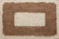 Frame made of rough burlap lies on rice grains Royalty Free Stock Photo