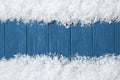 Frame made of snow on blue wooden background, top view with space for text. Christmas time Royalty Free Stock Photo