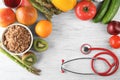 Frame made with stethoscope, fresh fruits and vegetables on wooden background. Healthy food concept Royalty Free Stock Photo